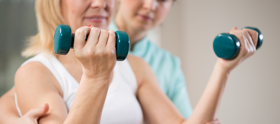 Cropped photo for woman helping older woman bicep curl small weights